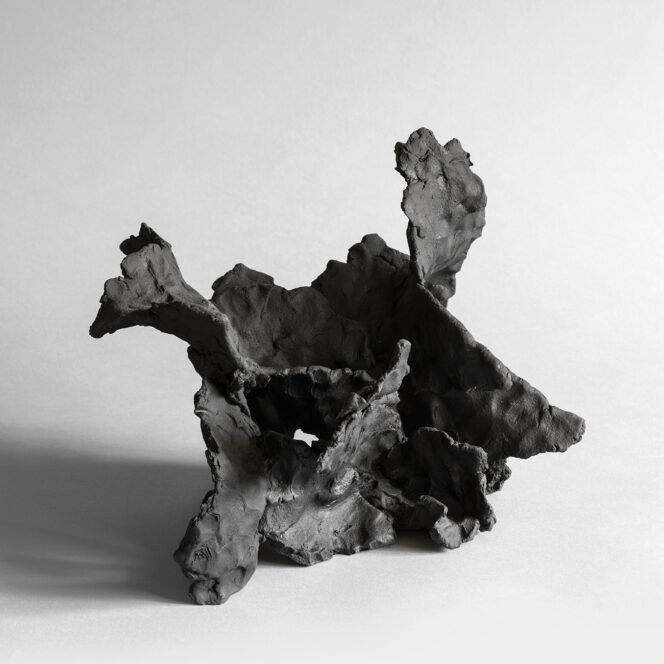 Dark stoneware sculpture with wave-like forms and textured surface, resembling drift or motion.