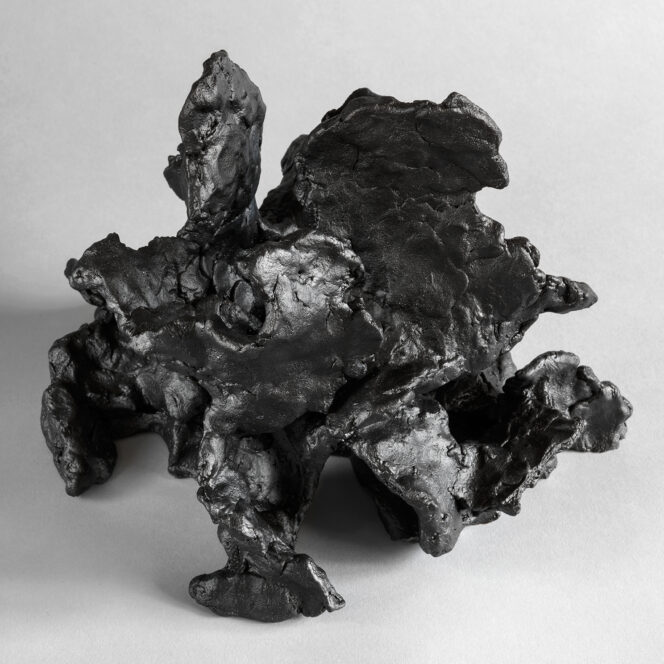 Dark stoneware sculpture with layered, organic textures and a fluid, wave-like composition.