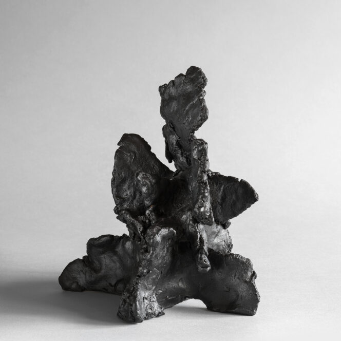 Dark stoneware sculpture with upward, organic folds and a textured, wave-like surface.