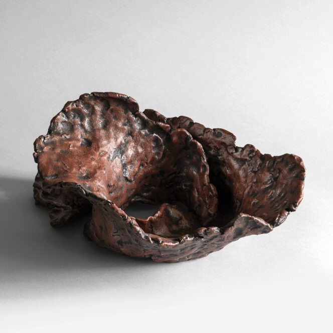 Elongated hand-built stoneware sculpture with swirling ridges and textured red surface.
