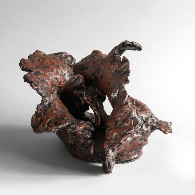 Hand-built stoneware sculpture with twisting, layered forms and warm red-brown surface.